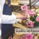 Floristin arrangiert rosa und lila Rosen neben Trodat Stempeln für personalisierte Verpackungen