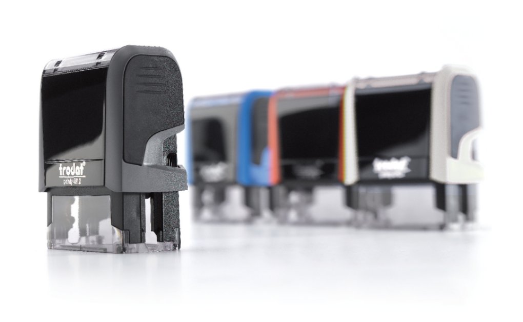 Trodat Printy 4912 in Schwarz mit weiteren farbigen Gehäusevarianten im Hintergrund.